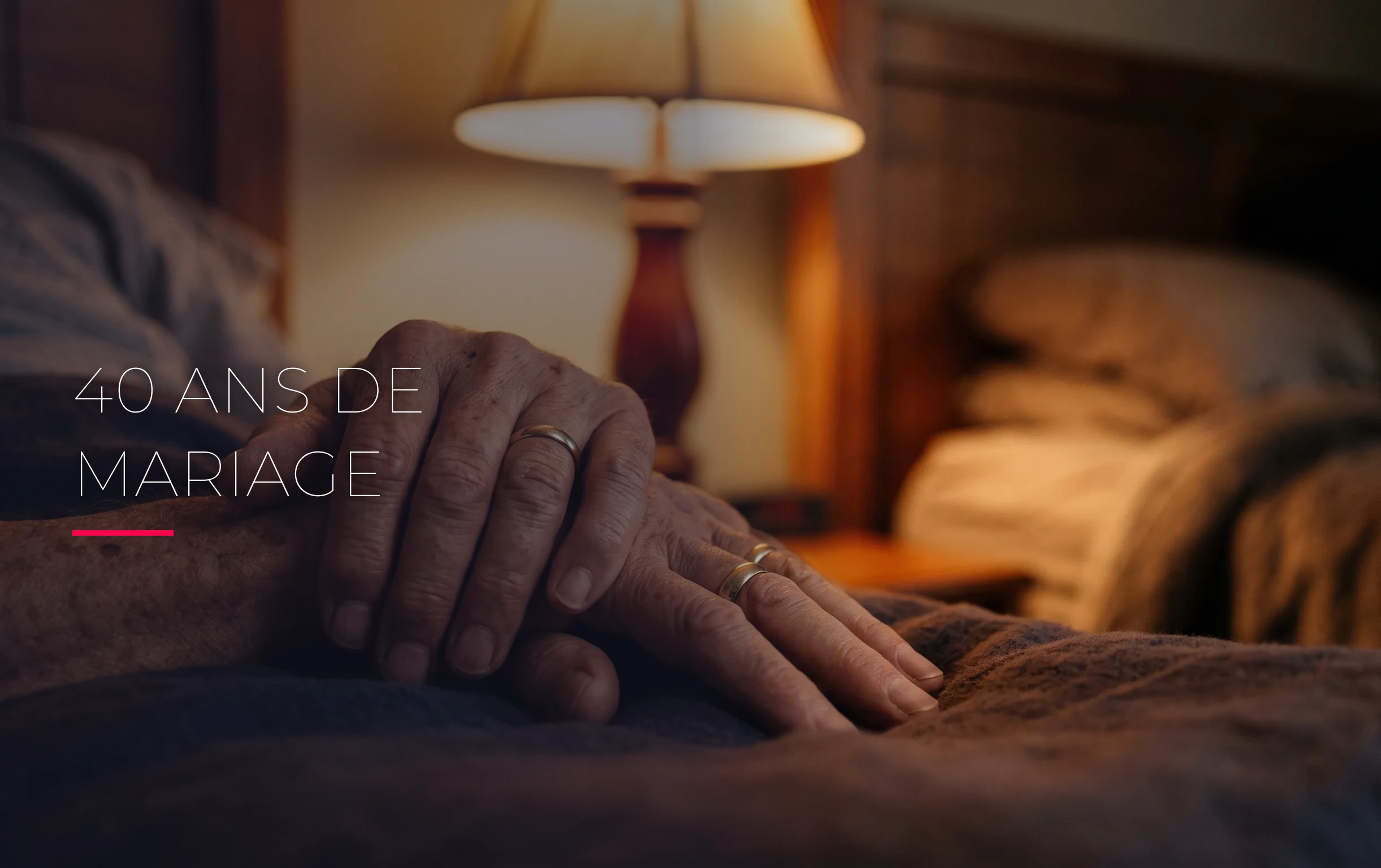 40 ans de mariage : noces d'émeraude ou simple routine ? 1 Deux mains âgées portant des alliances entrelacées sous la lumière chaleureuse d'une lampe de chevet