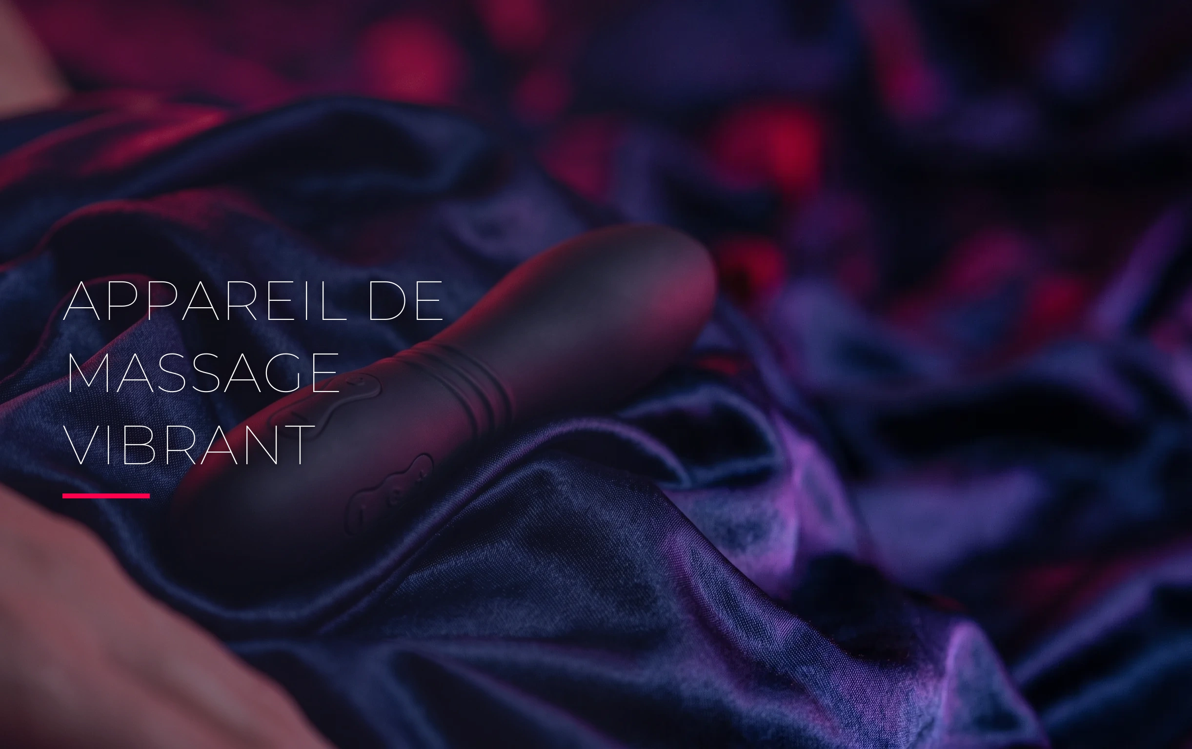 Un appareil de massage vibrant noir mat posé sur des draps en satin froissés sous une lumière néon cerise et violette