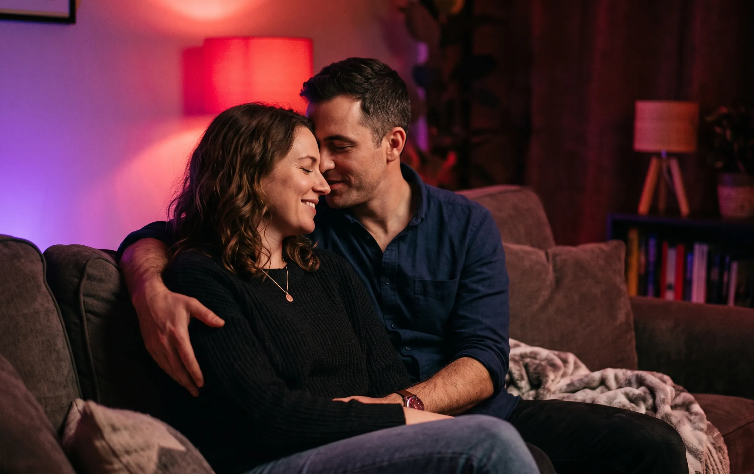 branlette espagnole : Un couple complice partageant un moment intime dans un salon baigné d'une lumière néon rouge cerise