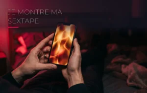 Un téléphone portable affichant une lueur chaleureuse tenu dans la pénombre d'une chambre aux tons rouge cerise