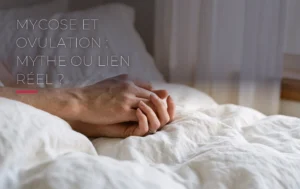 Des mains enlacées sur des draps en coton blanc baignées par une douce lumière naturelle évoquant le cycle féminin