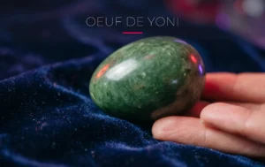 Un œuf de yoni en jade poli posé sur du velours sombre mis en valeur par un éclairage néon cerise